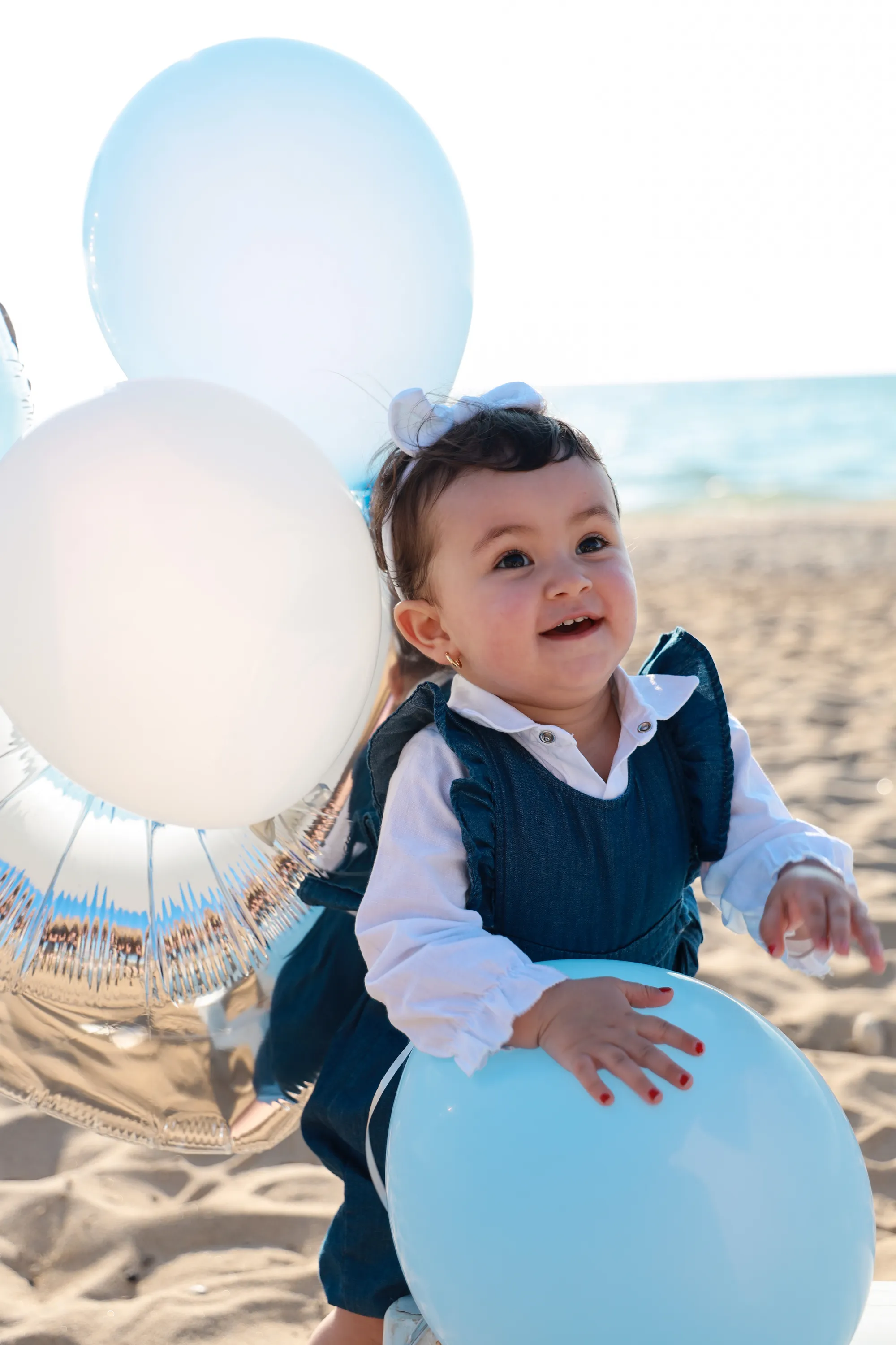 Toddler smiling beside a white balloon at a beach party